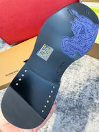 Black boot outsole with embossed logo and small metal stud accents on strap edge