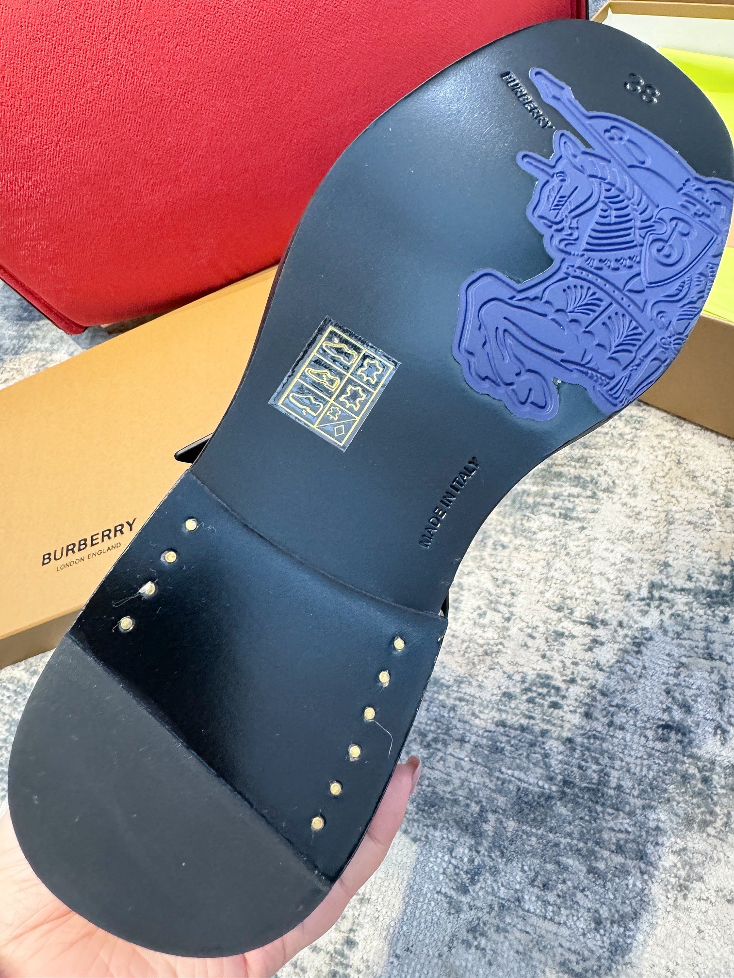 Black boot outsole with embossed logo and small metal stud accents on strap edge