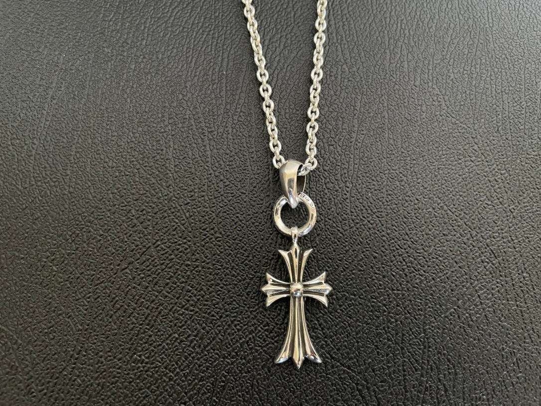 Silver-tone cross pendant necklace with heart-shaped bail and starburst cross arms