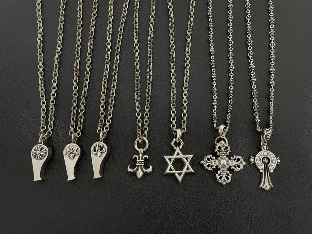 Silver-tone charm necklaces set with assorted pendants on chain, including fleur-de-lis and star.