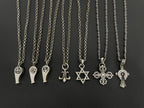 Silver-tone charm necklaces set with assorted pendants on chain, including fleur-de-lis and star.