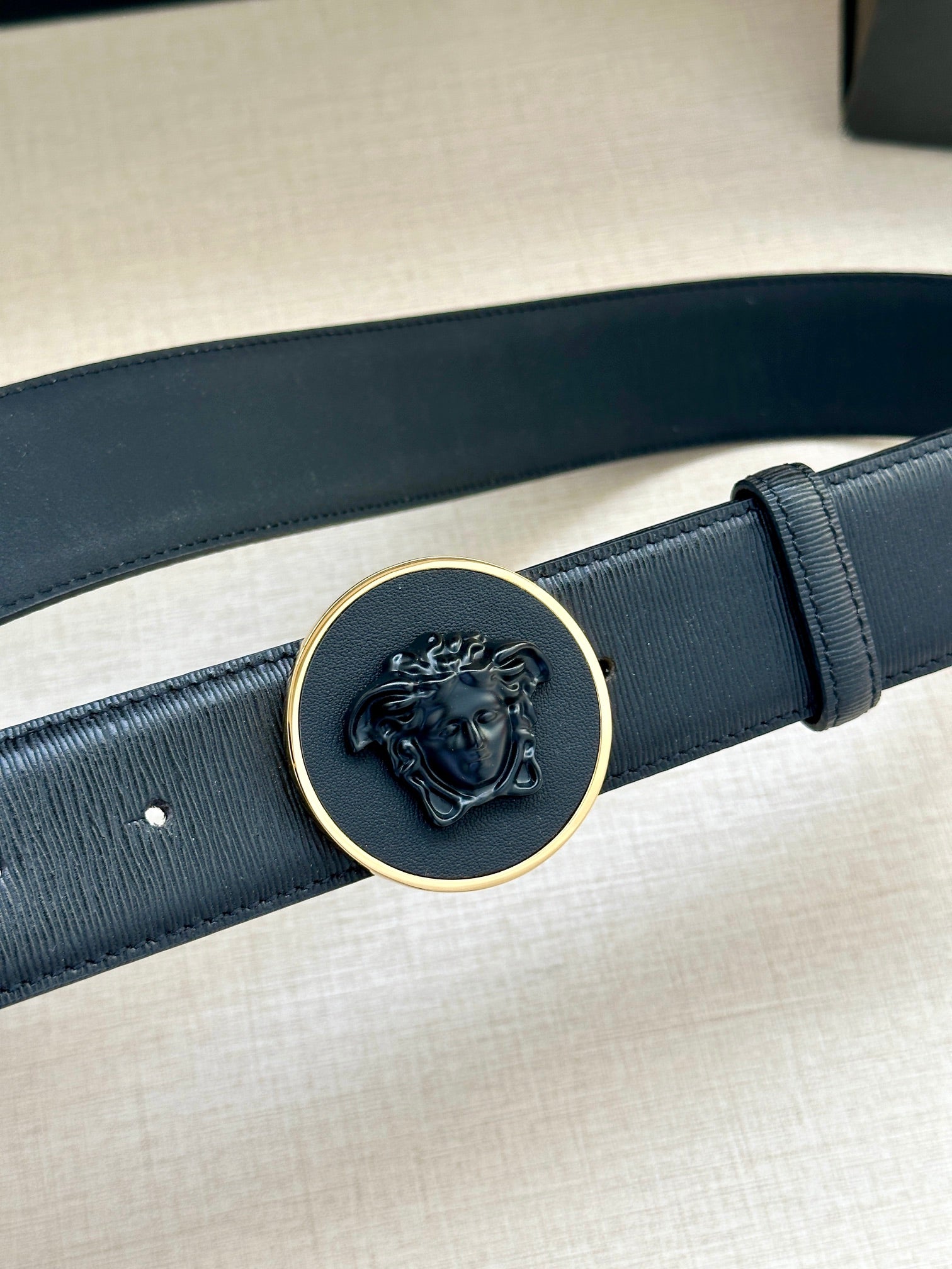 Versace belt with gold-tone circular emblem buckle on dark blue strap