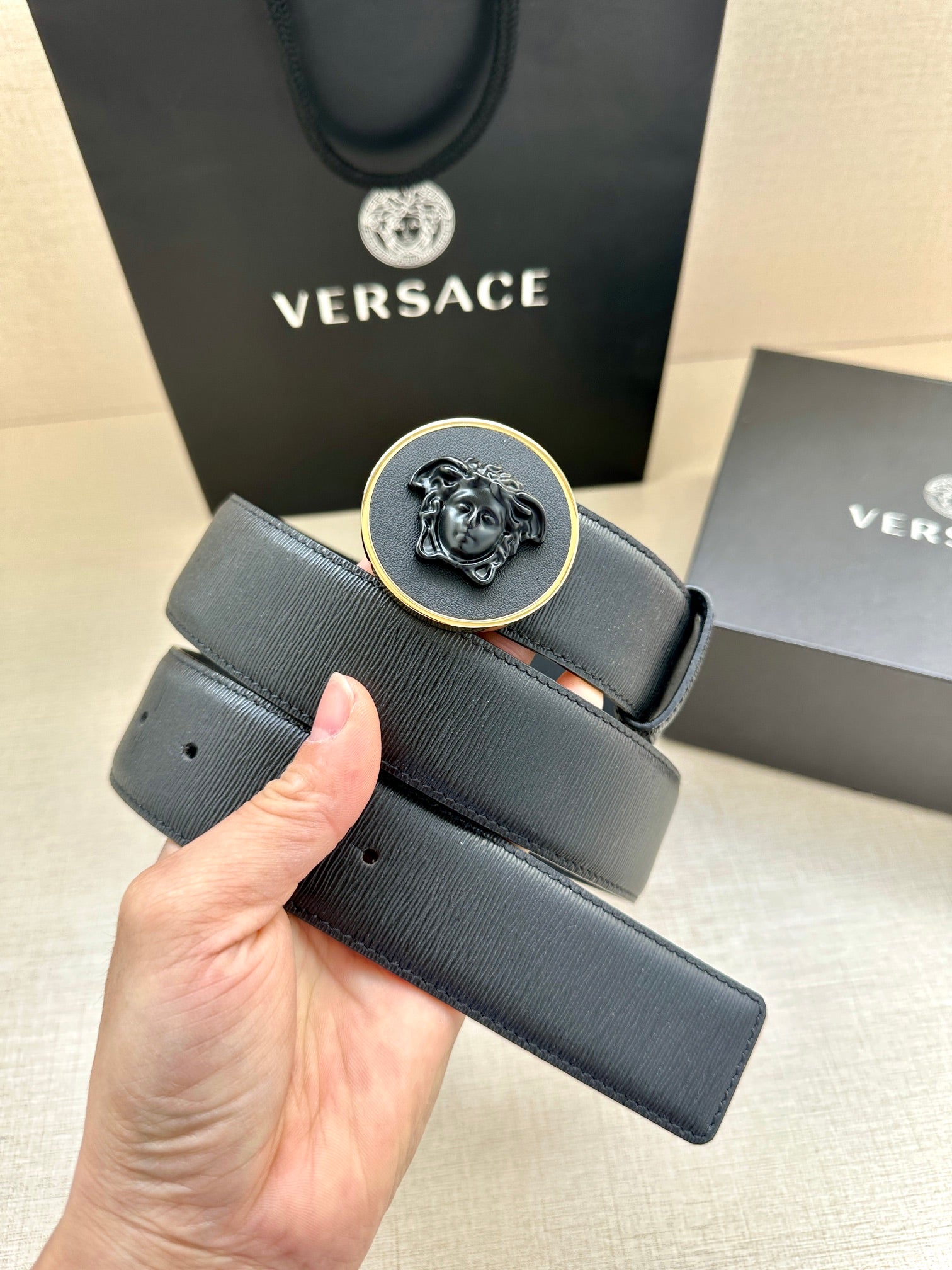 Versace belt buckle close-up with dark blue embossed leather strap