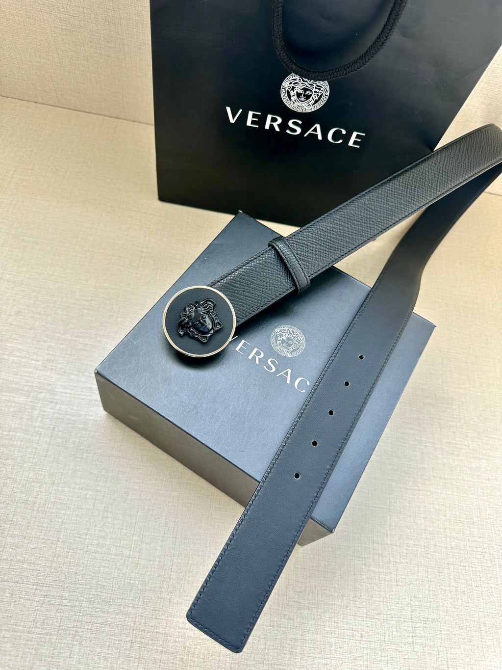Dark blue leather-look belt with round logo buckle on embossed brand box