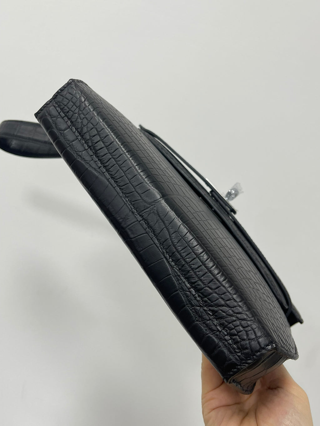Hermes bag angled view with dark crocodile texture, zipper edge and top handle