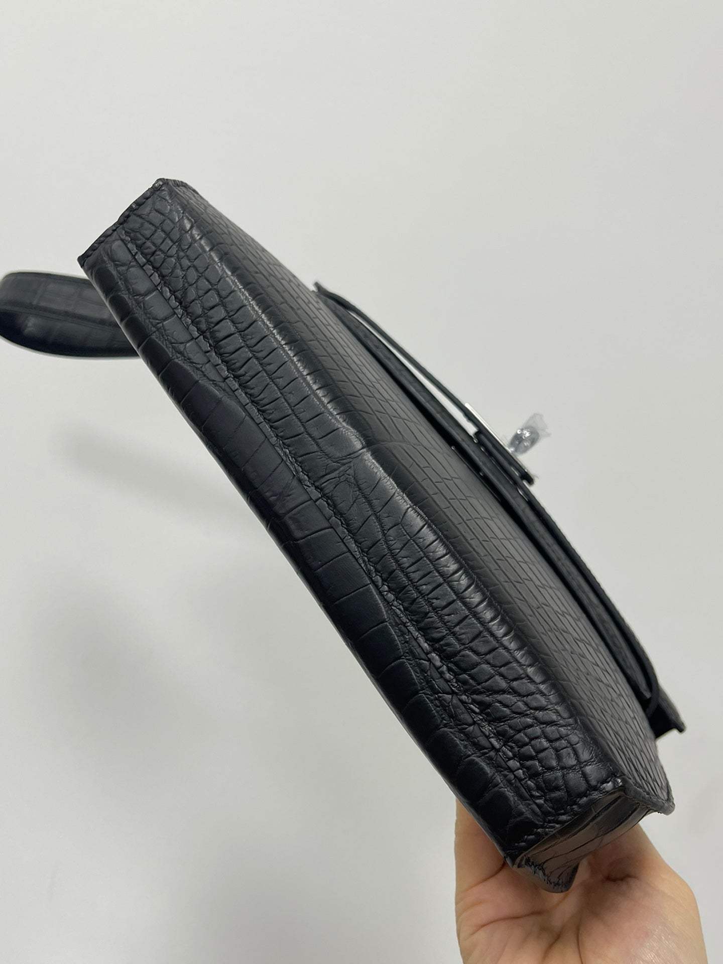 Hermes bag angled view with dark crocodile texture, zipper edge and top handle