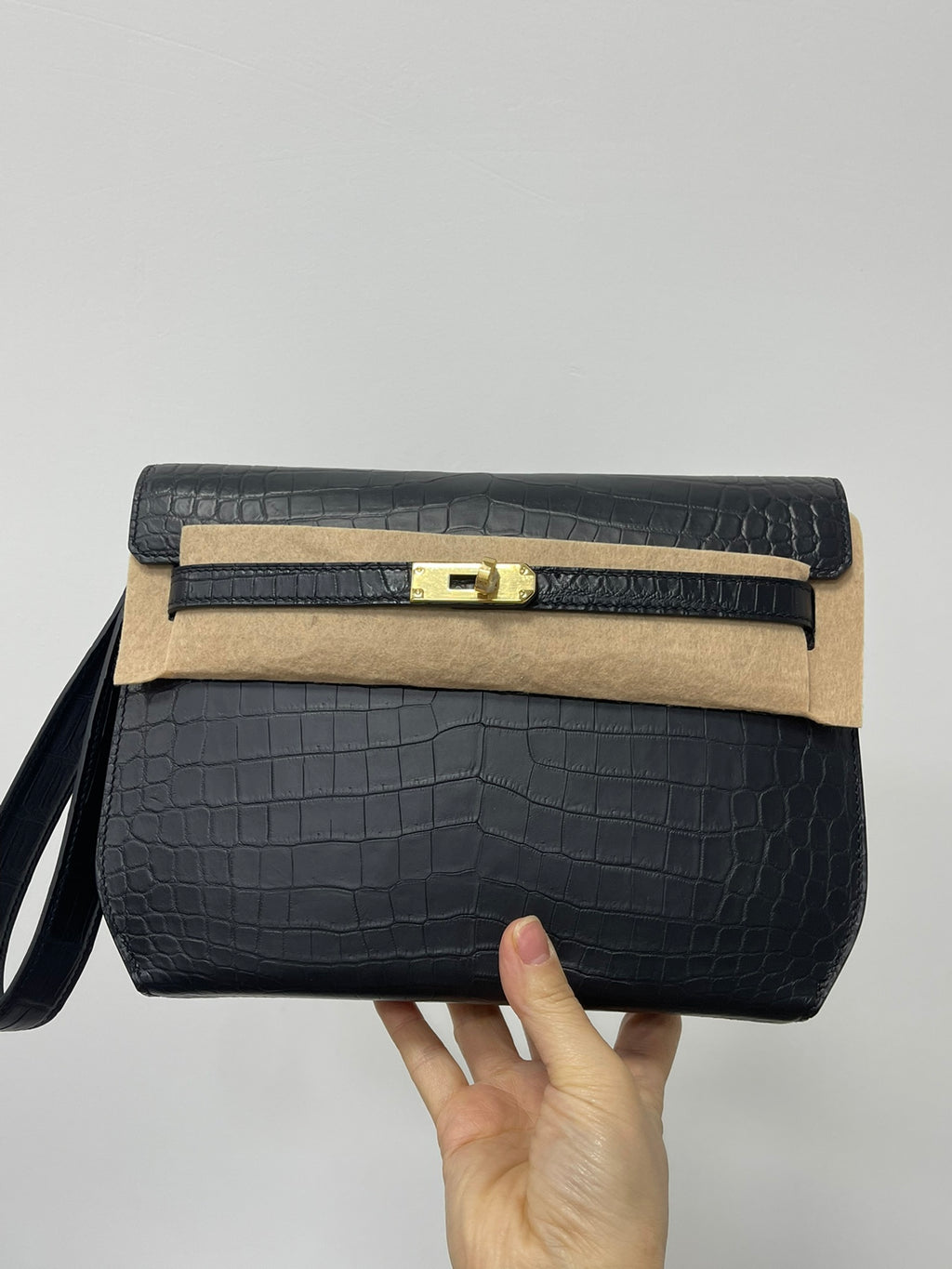 Hermes bag, dark croc-textured flap with gold clasp, beige panel, wrist strap