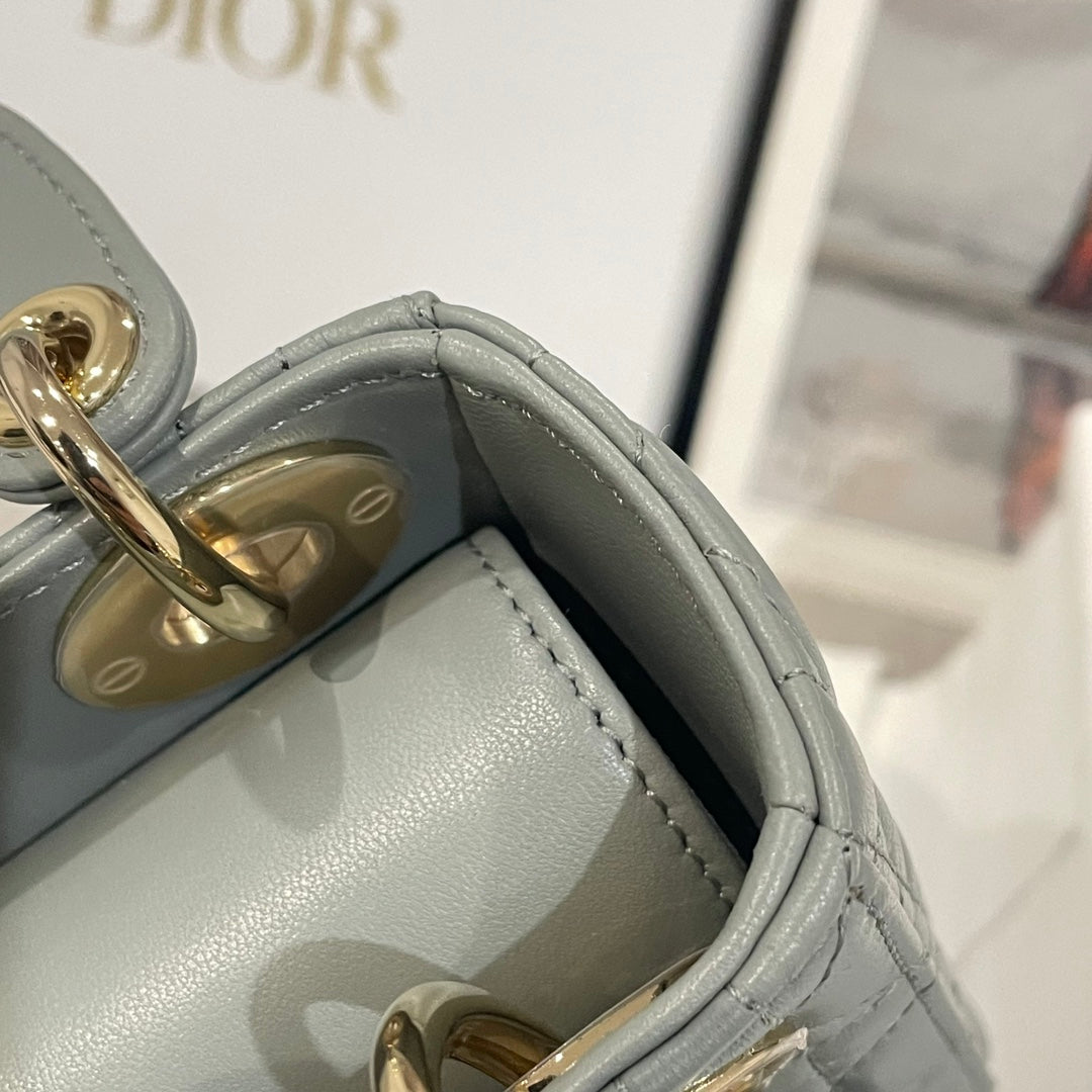 Dior handbag interior side panel with stitched light blue-gray leather and gold details.