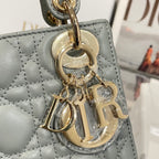 Dior handbag charm and gold hardware on light blue-gray quilted leather panel.