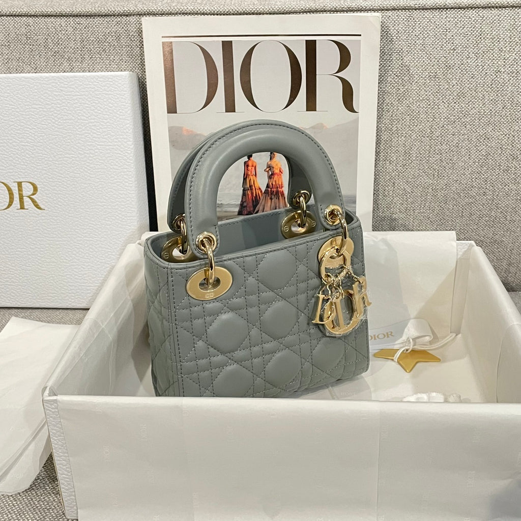 Dior quilted mini handbag with top handles, light blue-gray leather, gold hardware and charm.
