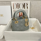 Dior quilted mini handbag with top handles, light blue-gray leather, gold hardware and charm.