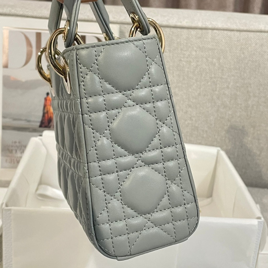Dior quilted mini handbag back view with strap, light blue-gray leather and gold hardware.