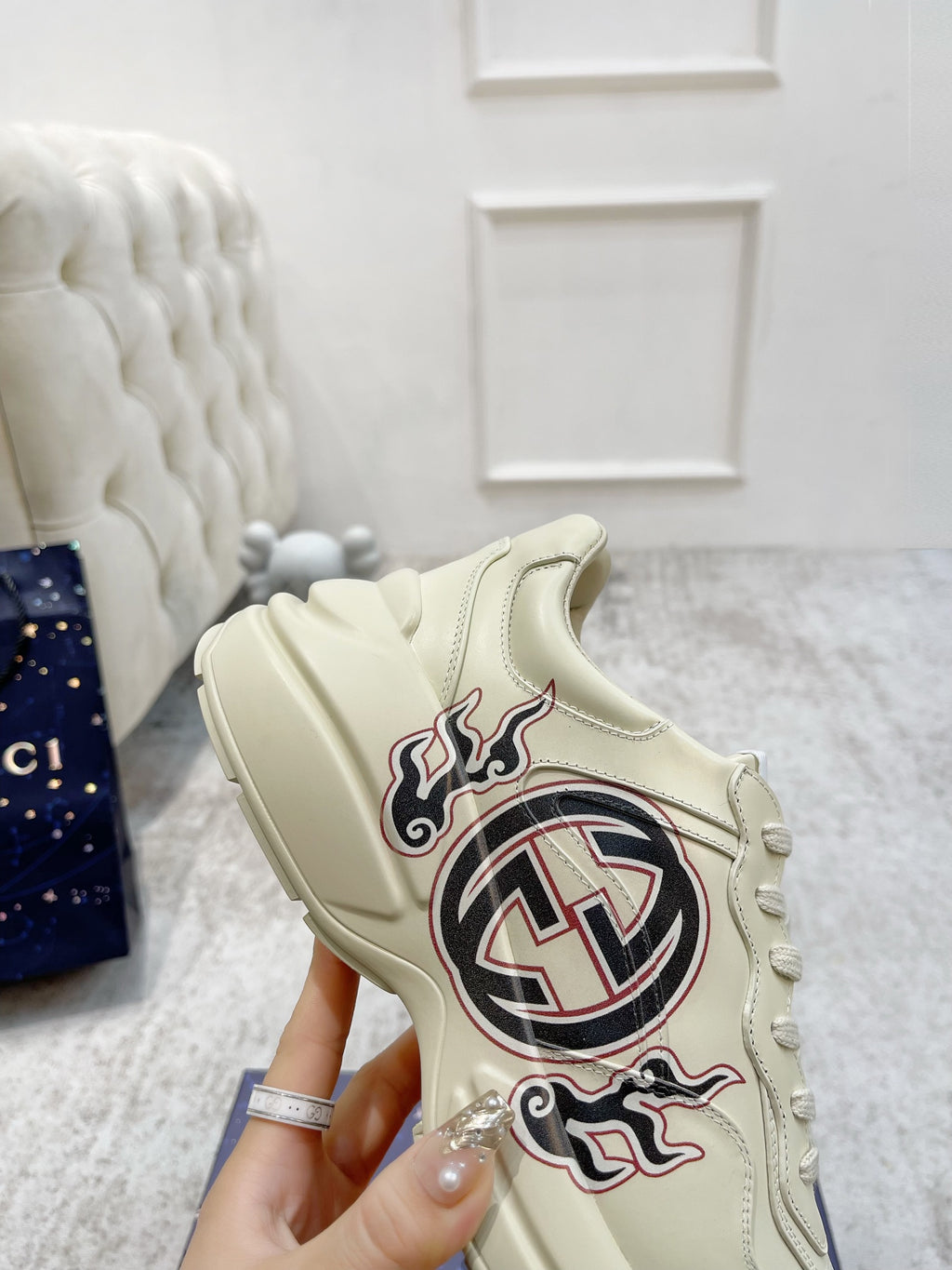 Gucci unisex luxury sneakers close-up, cream with GG logo and flame graphic