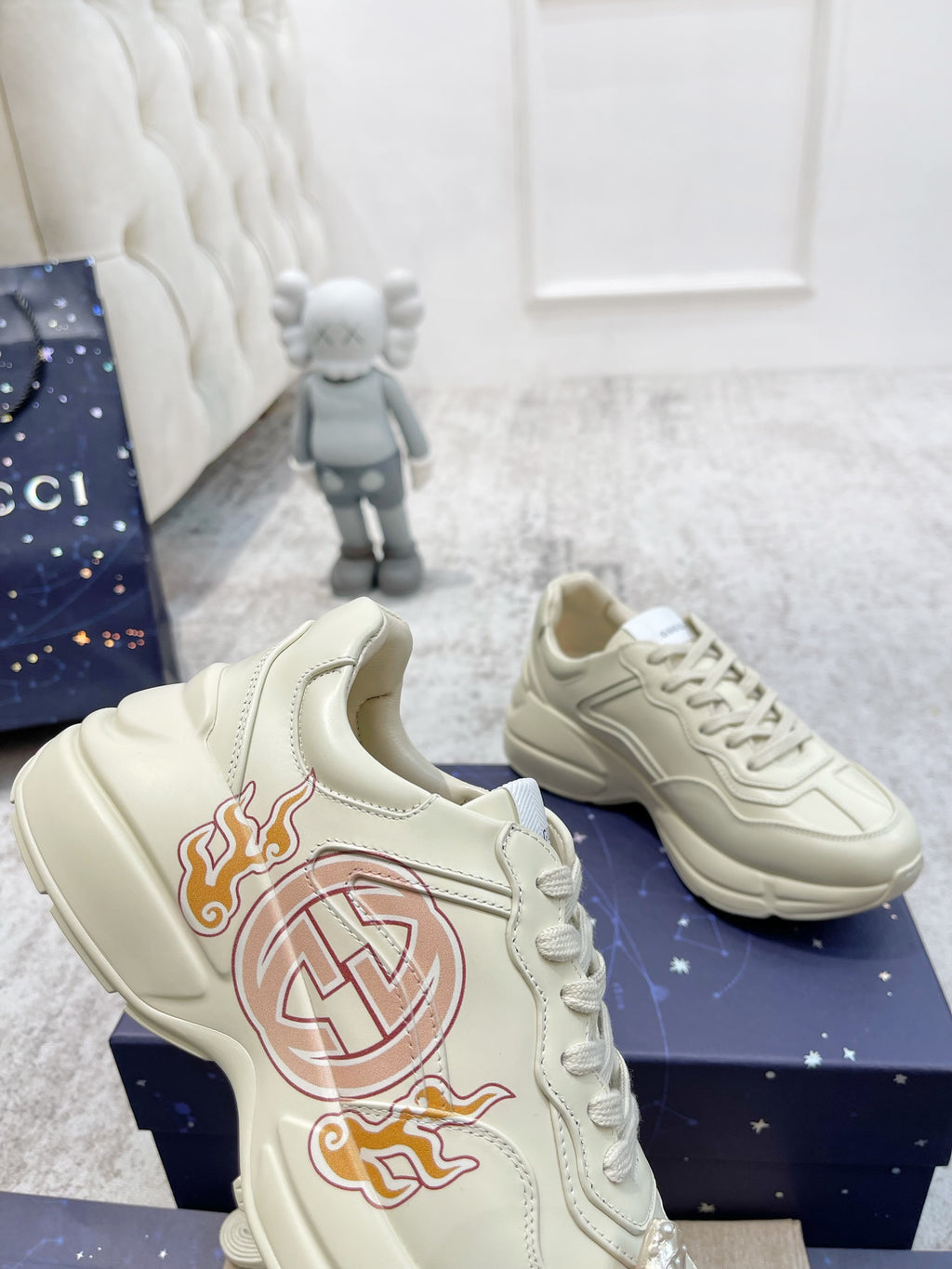 Gucci unisex luxury sneakers, light cream side view with red crest and orange flame print