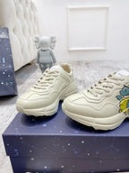 Cream Gucci unisex sneakers on blue box, lace-up with side graphic detail