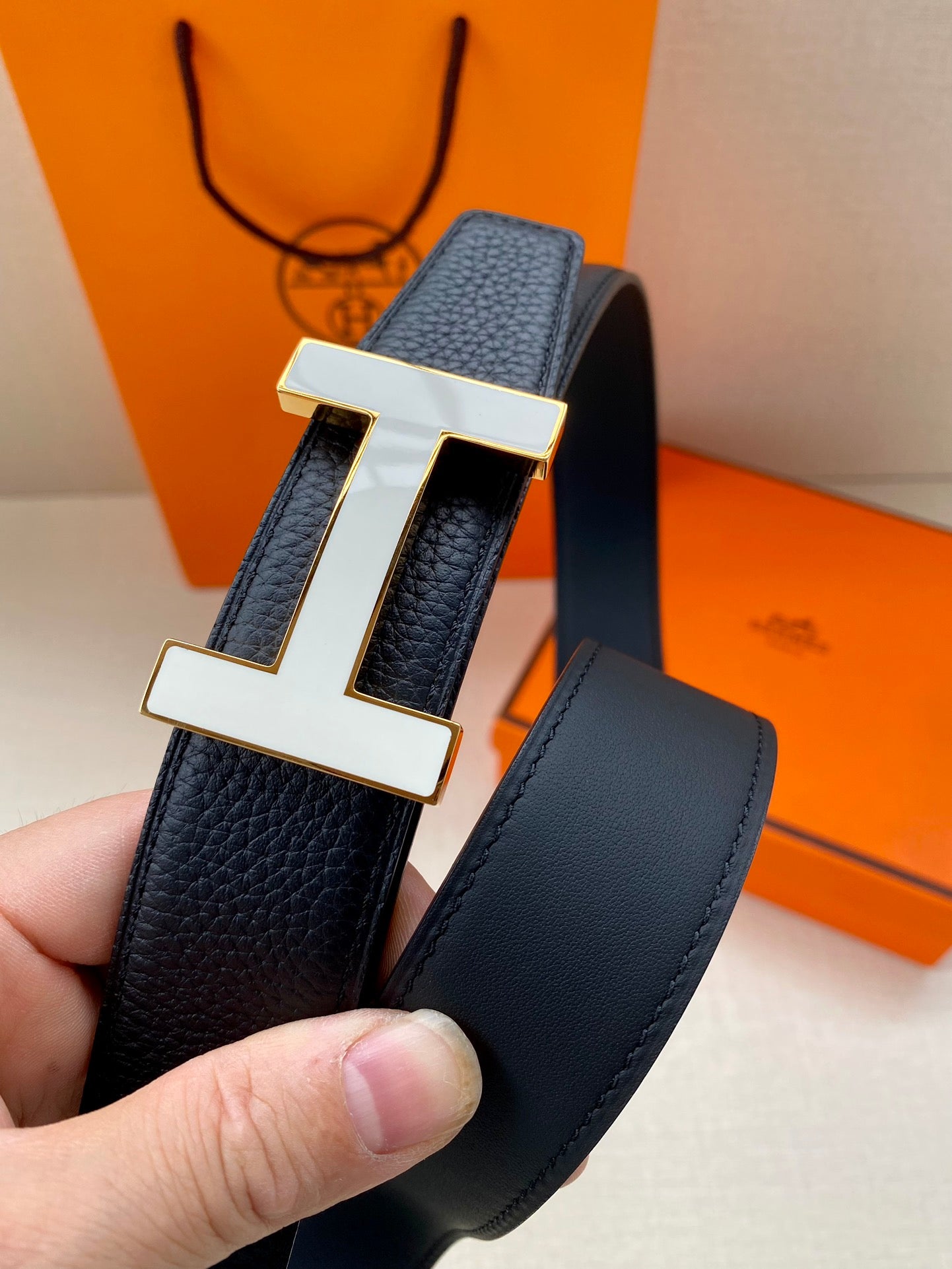 Hermes belt showing silver H buckle on dark leather strap
