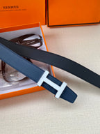 Blue leather belt with silver H buckle, stacked with a dark strap in box.