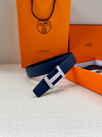 Blue leather belt with silver H buckle, styled on a surface with boxes.