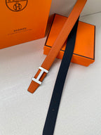 Hermes belt laid flat: orange leather with silver H buckle and dark strap