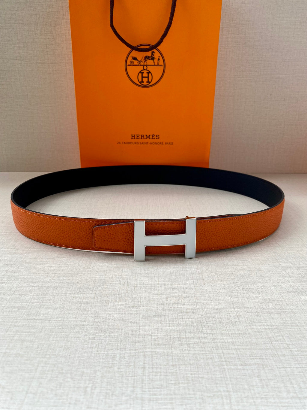 Hermes belt with orange leather and silver H buckle, dark lining visible