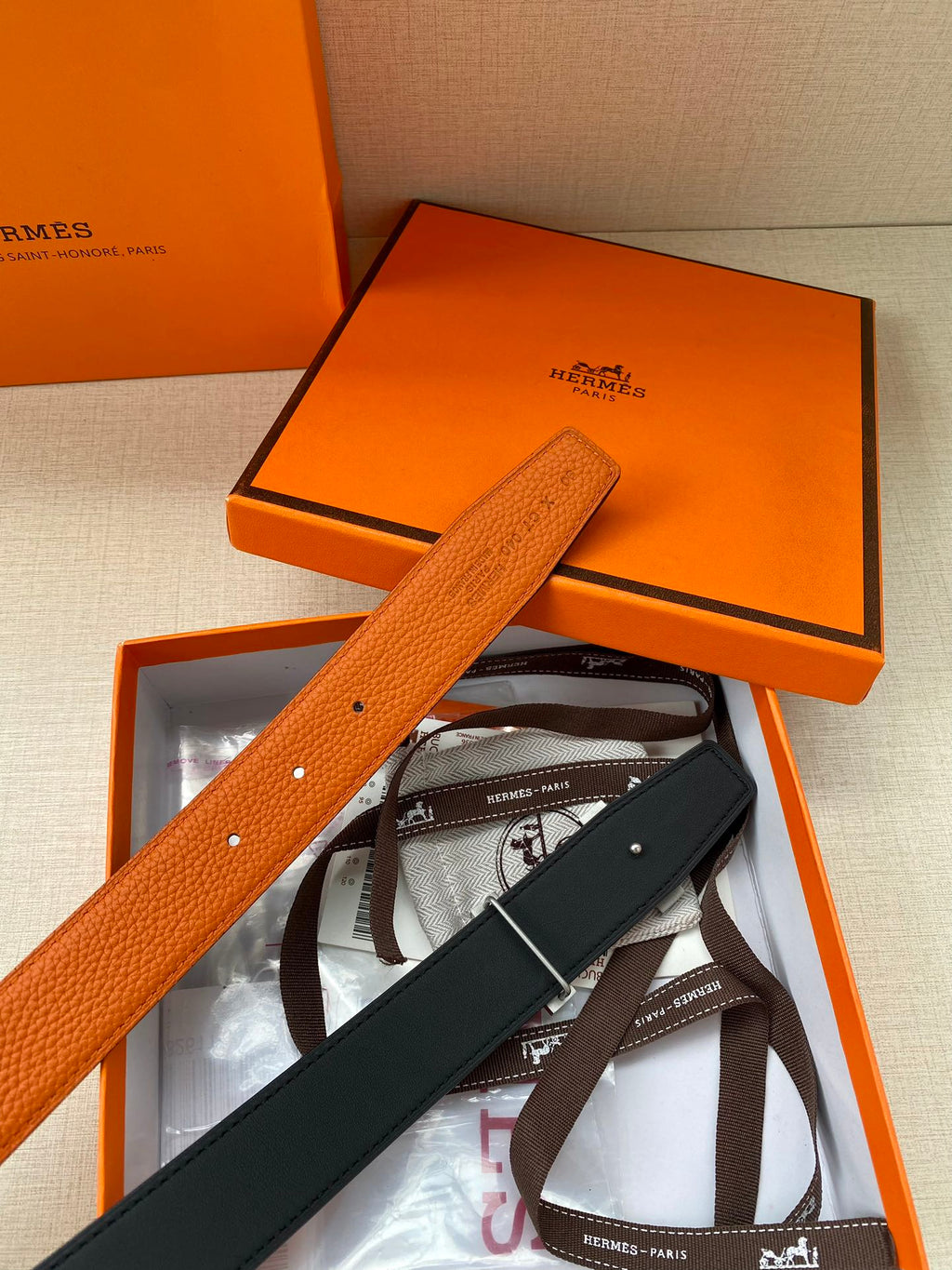 Hermes belt in orange textured leather with silver H buckle, shown with box insert
