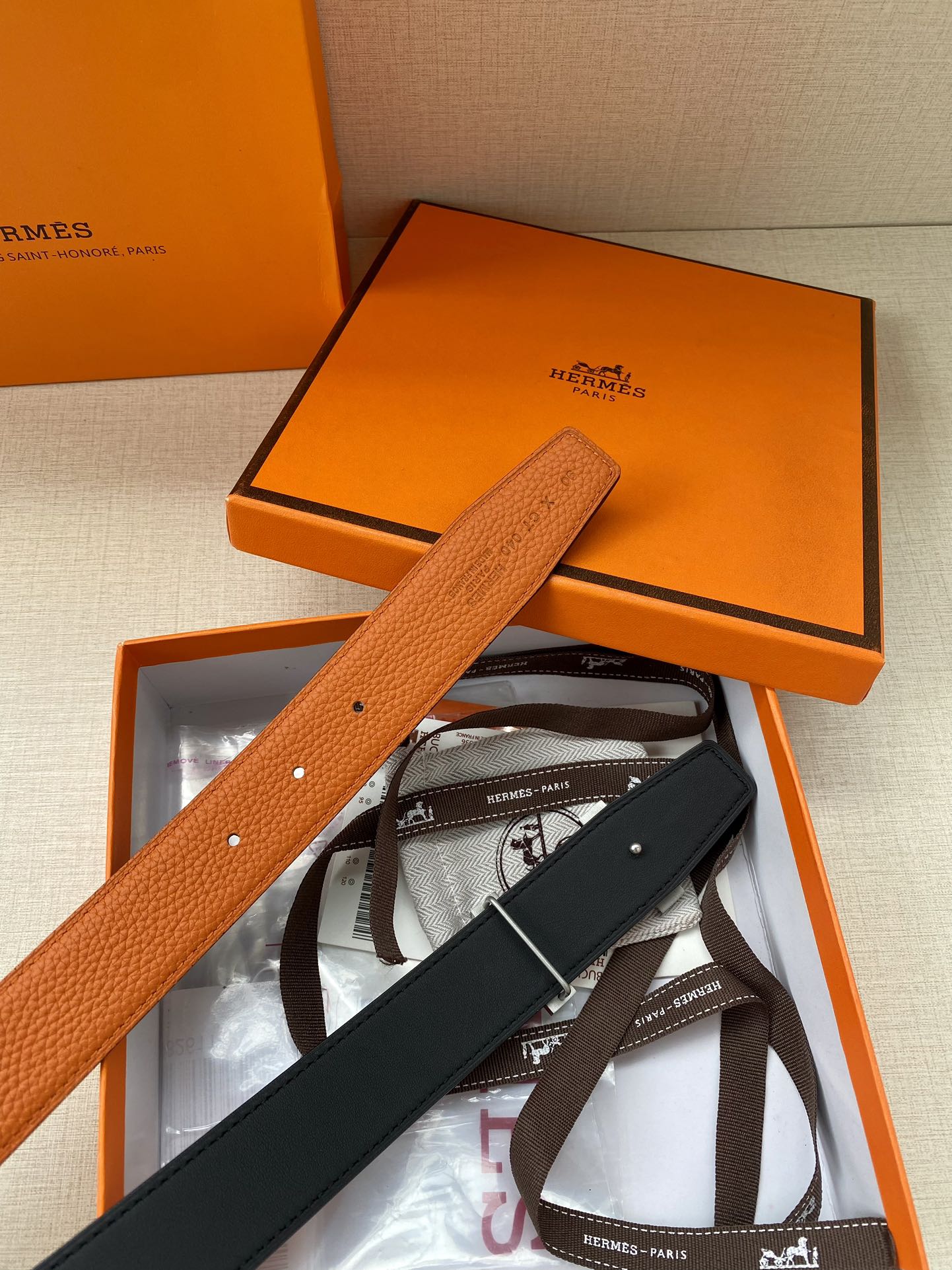 Hermes belt in orange textured leather with silver H buckle, shown with box insert