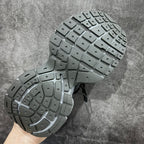 Shoe outsole with deep rubber tread, showing two gray soles held up