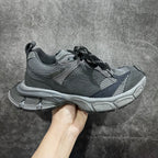 Gray athletic sneakers with mesh panels, black laces, and chunky silver sole