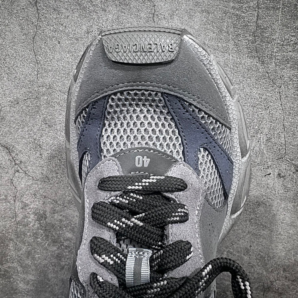 Close-up of lace-up sneaker with gray suede, mesh toe, and black shoelaces