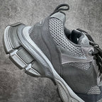 Gray athletic sneaker side view with mesh quarter, black laces, and raised sole