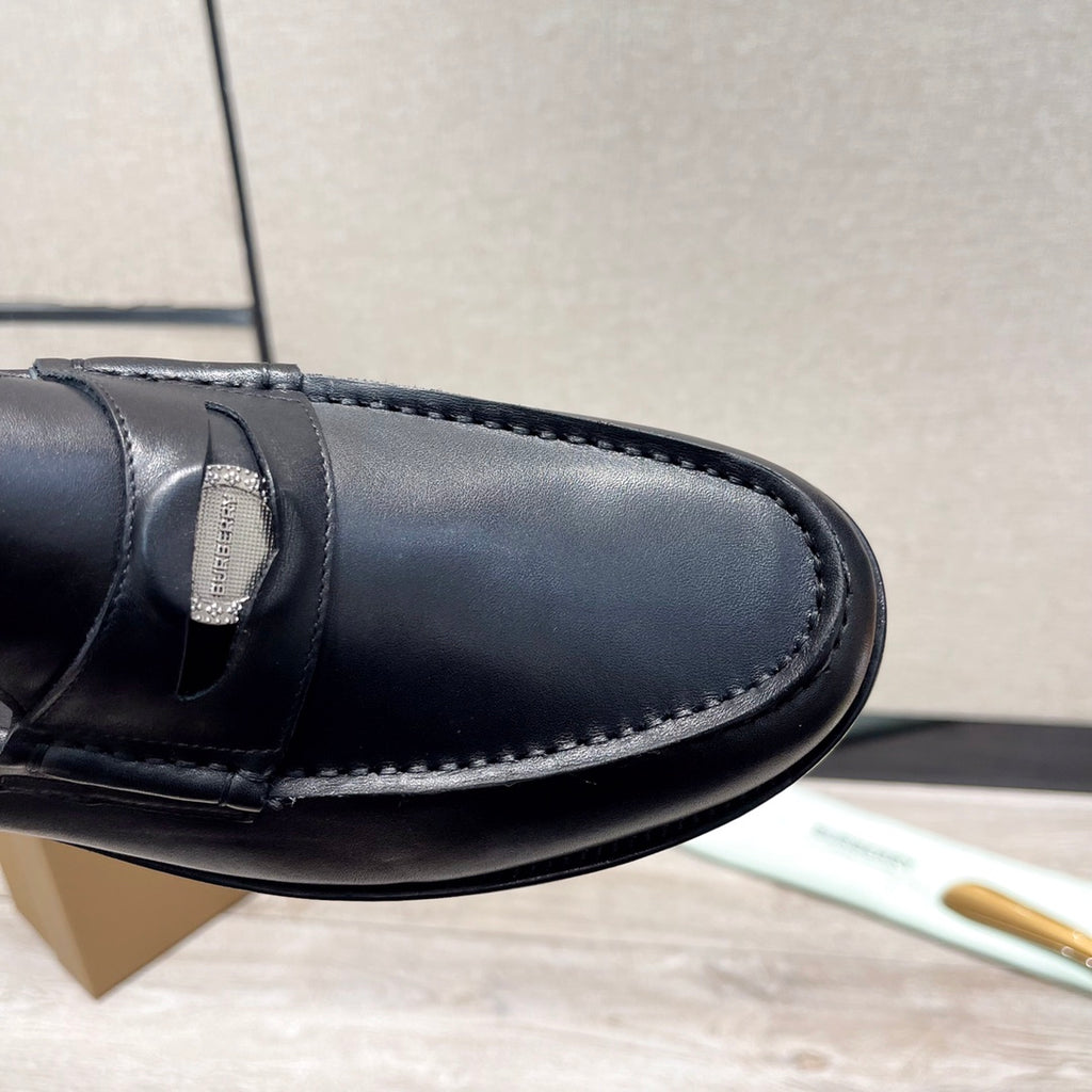 Black leather loafer toe with stitched apron and strap detail, close-up
