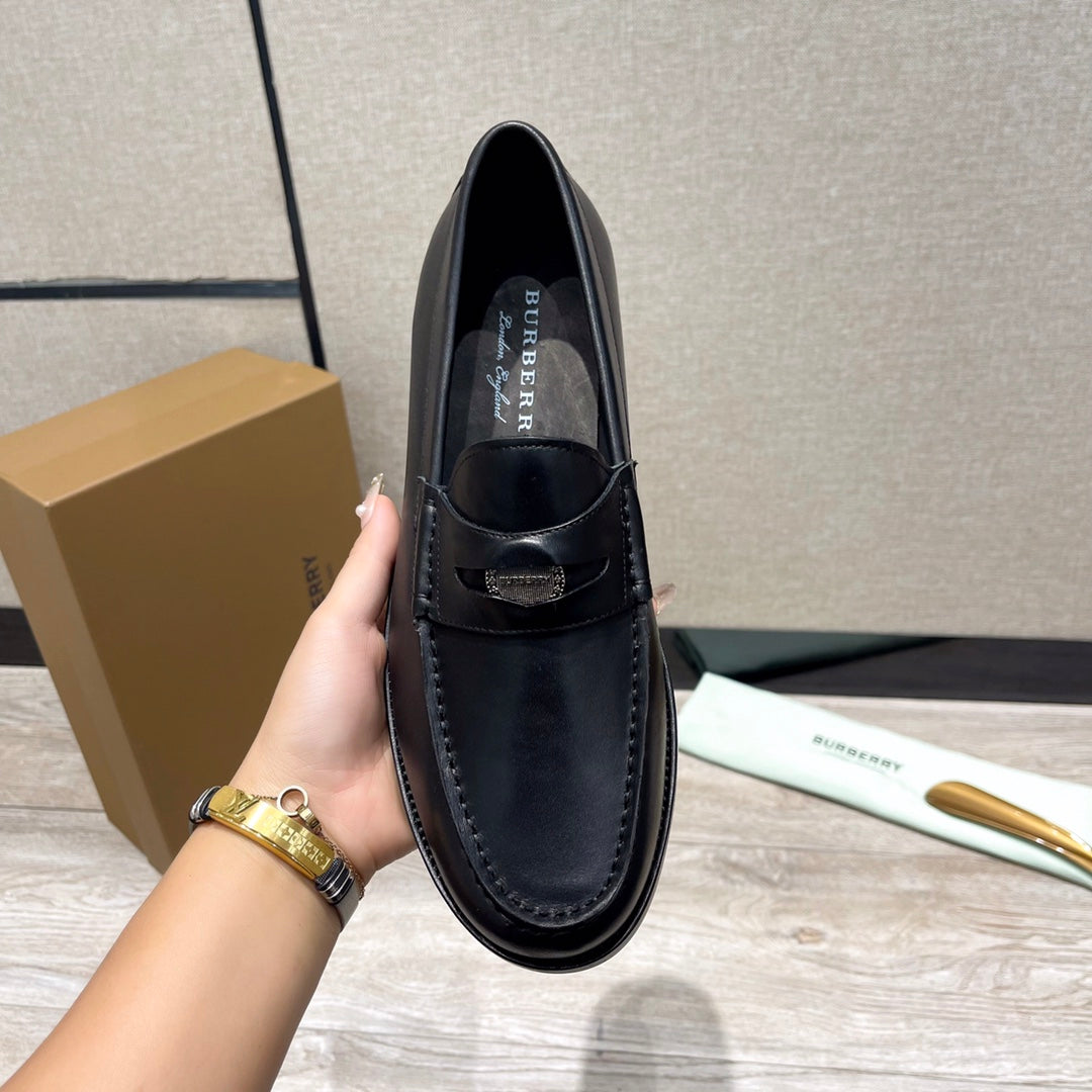 Black leather loafer with logo lining, shown from above by hand