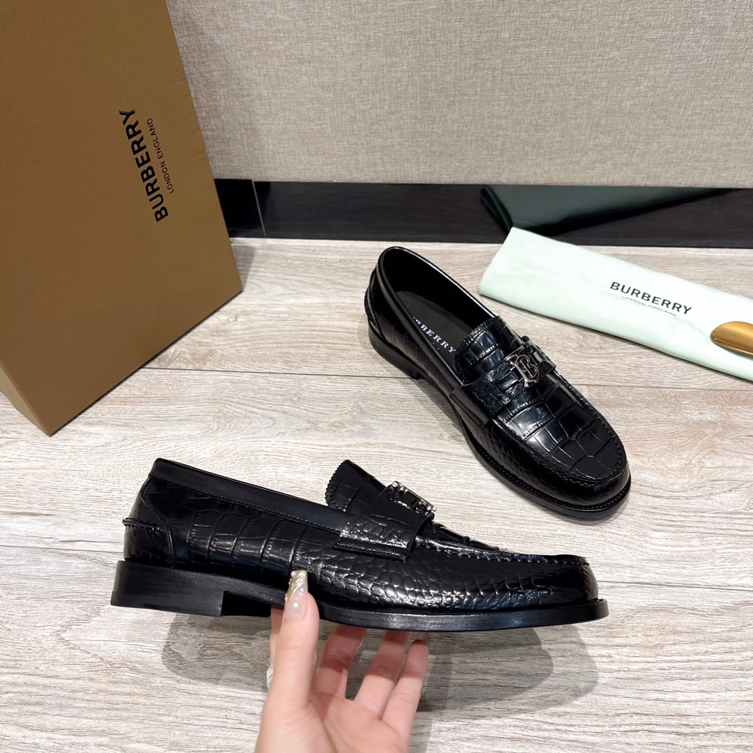 Black embossed leather loafer with metal buckle, showing sole and heel