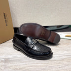 Black leather loafer with embossed texture and metal buckle, brown outsole