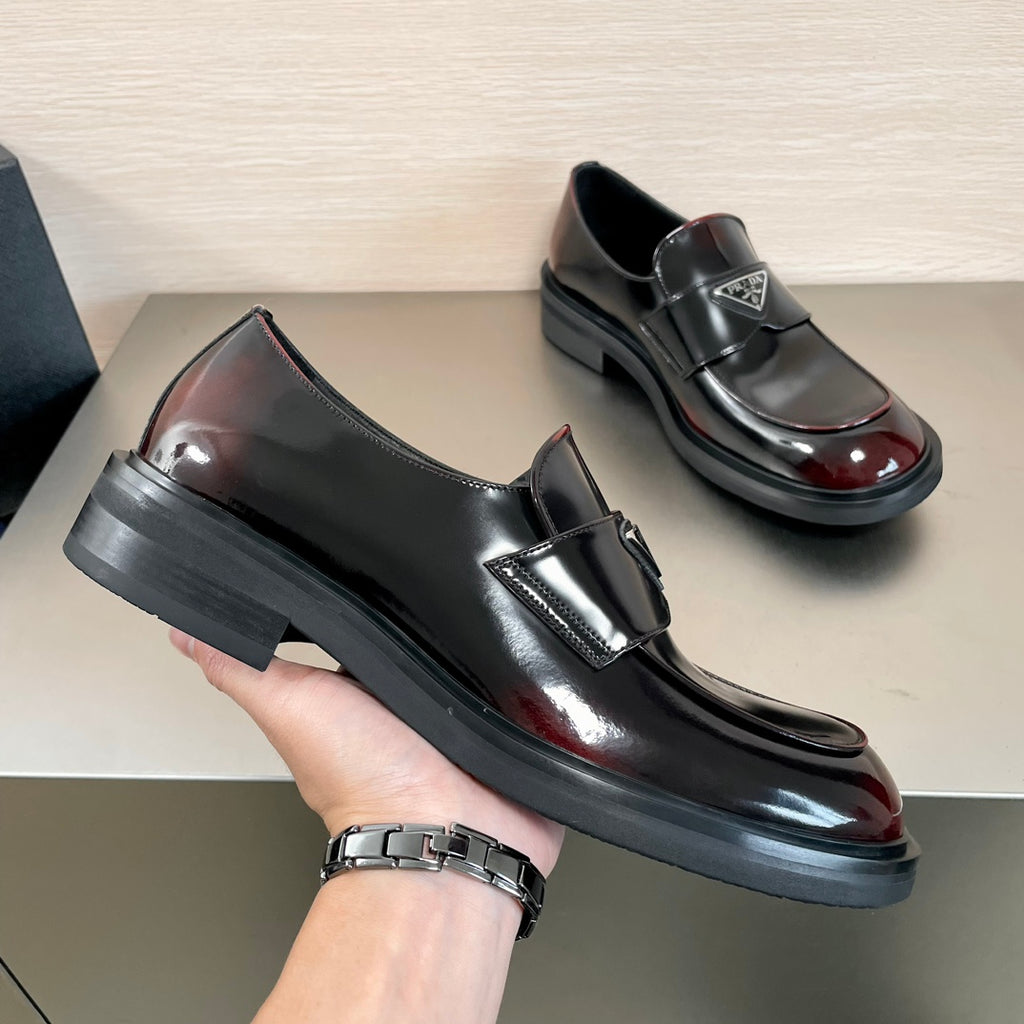 Prada unisex loafer shoe in hand, black leather slip-on with burgundy gloss toe