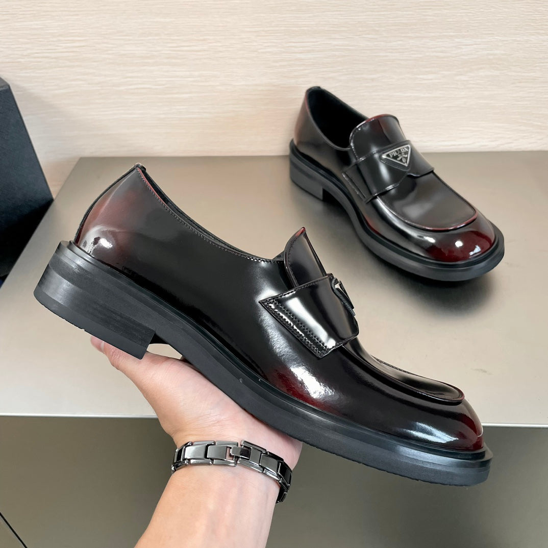 Prada unisex loafer shoe in hand, black leather slip-on with burgundy gloss toe