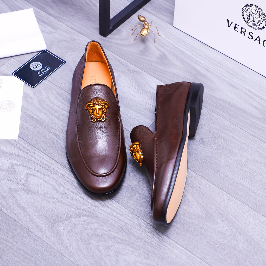 Brown leather slip-on loafers with gold Medusa emblem and side profile