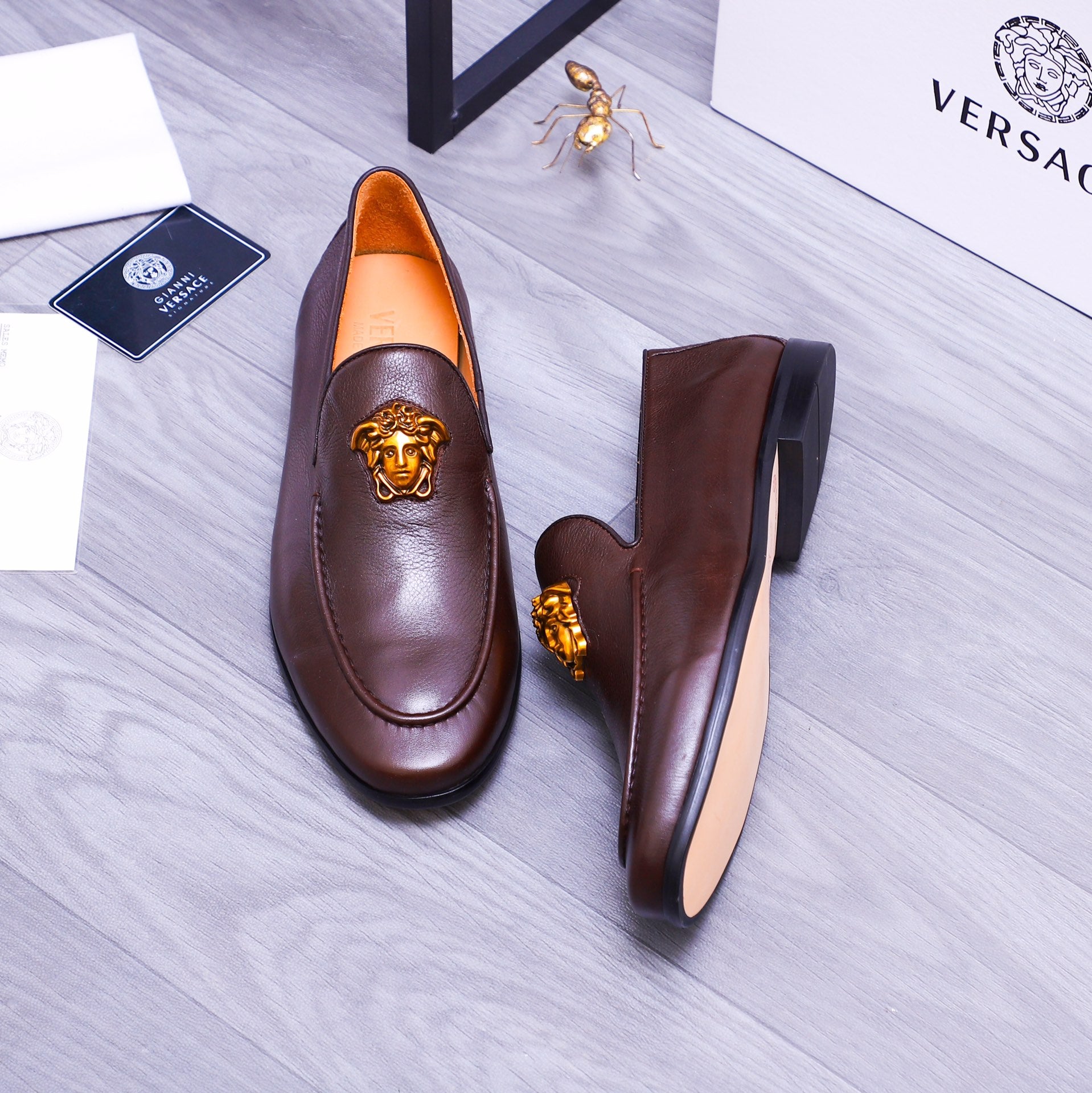 Brown leather slip-on loafers with gold Medusa emblem and side profile