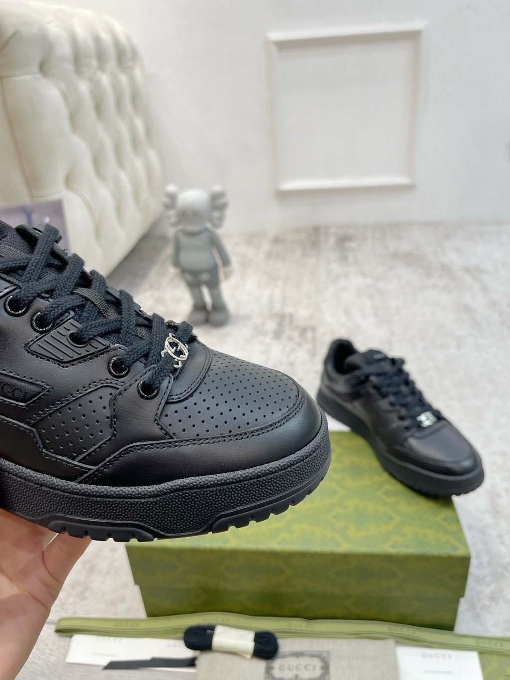 Gucci unisex low sneakers close-up, dark black leather-style with laces