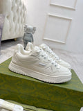 White Gucci unisex lace-up sneakers, side logo and perforated toe detail visible.