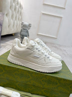 White Gucci unisex lace-up sneakers, side logo and perforated toe detail visible.