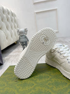 White Gucci unisex sneakers showing outsole tread pattern and logo at heel.