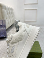 White Gucci unisex sneaker, side profile showing overlay stripes and thick grippy sole.