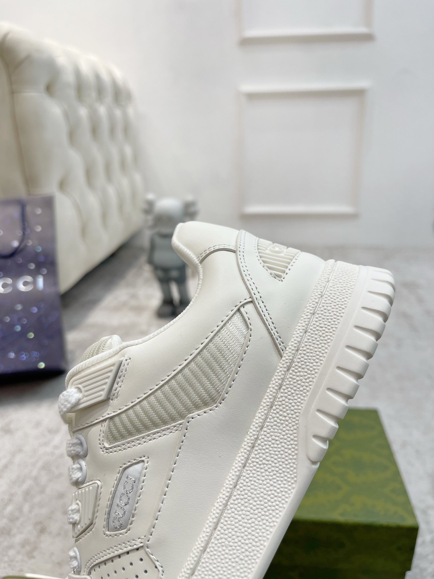 Gucci unisex luxury sneakers, white side view with embossed logo and tread sole