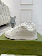 White Gucci unisex low-top sneakers with stitched overlay and lace-up front.