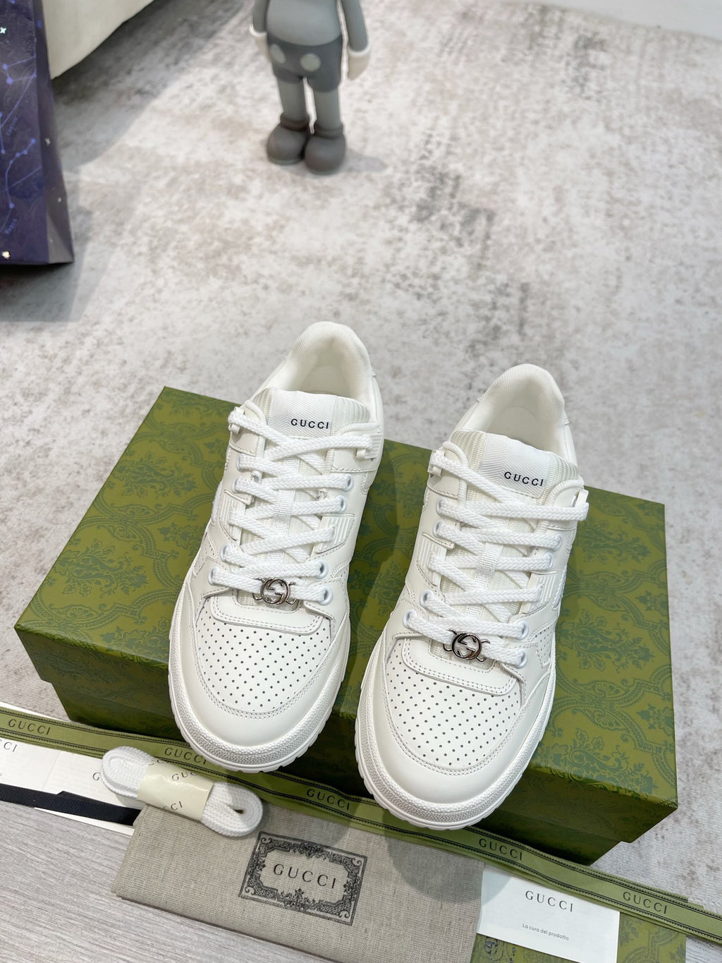 Pair of white Gucci unisex lace-up sneakers with logo strap on the midfoot.