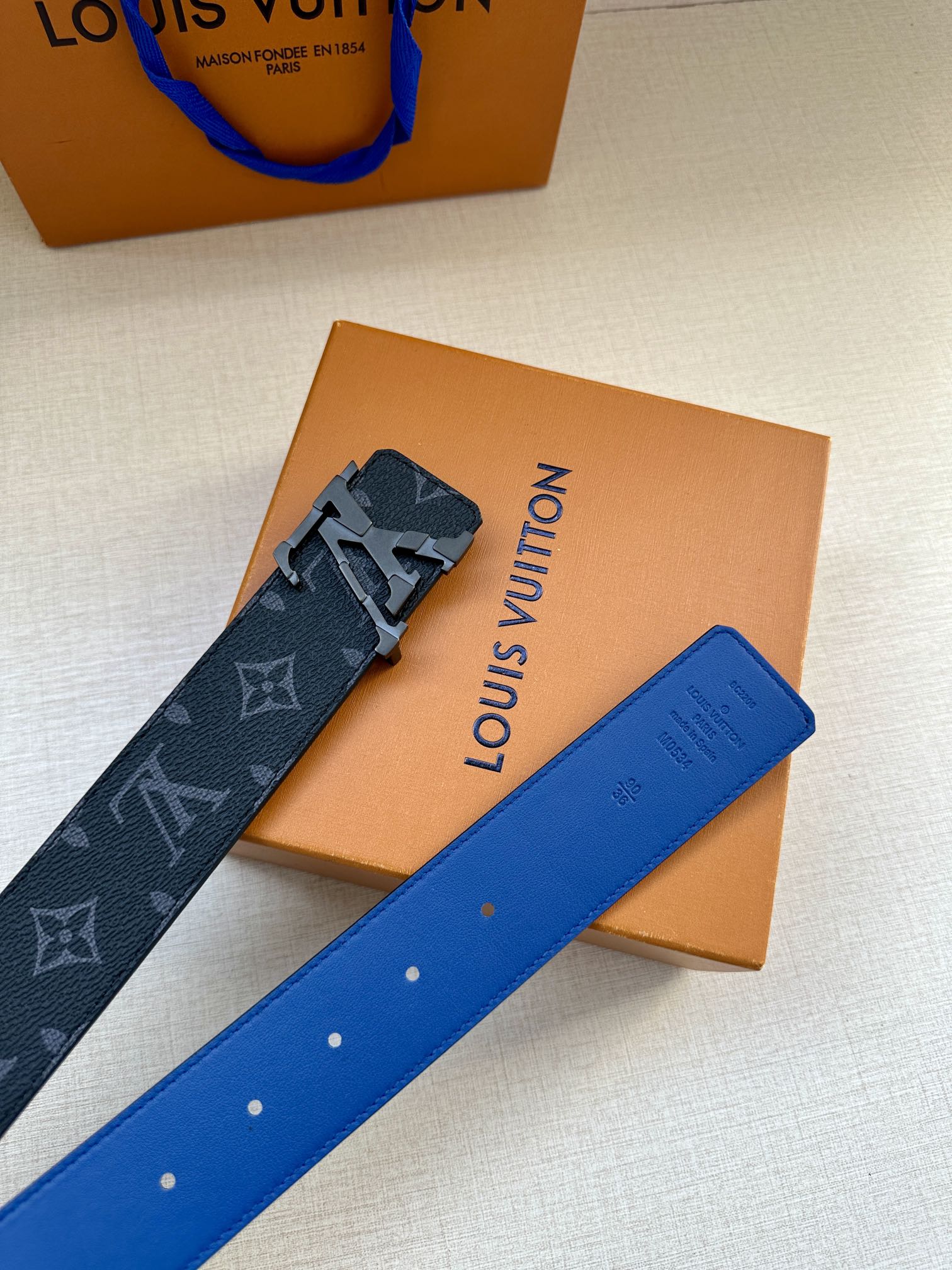 Louis Vuitton monogram belt with blue strap, silver buckle, and punched holes