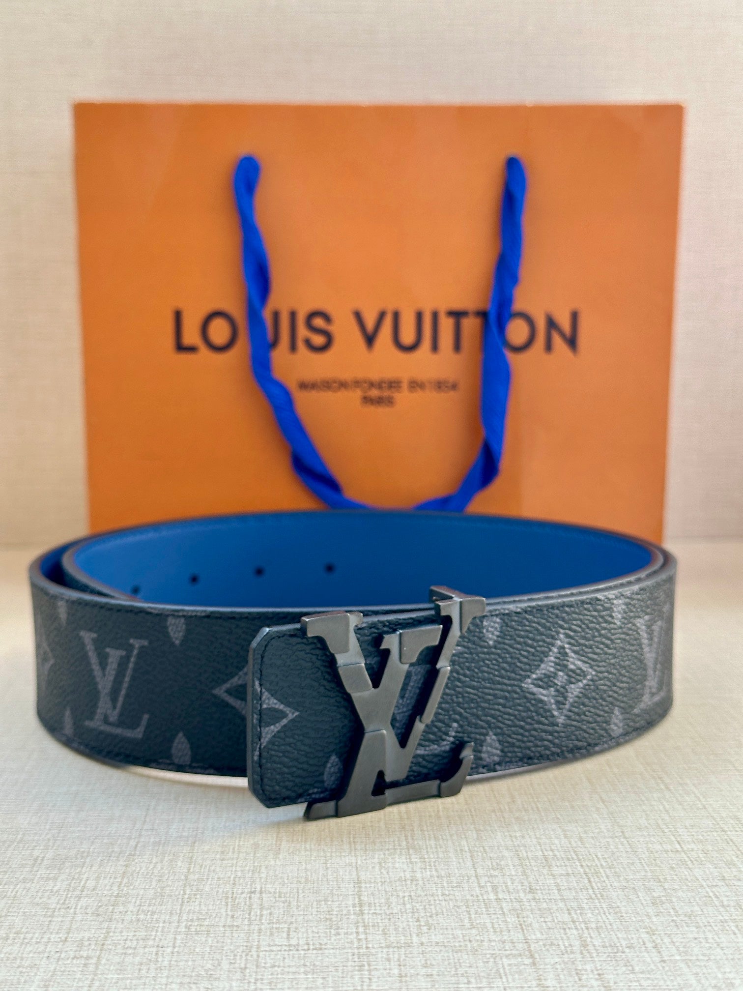 Louis Vuitton monogram belt with dark blue strap and prominent metal buckle center