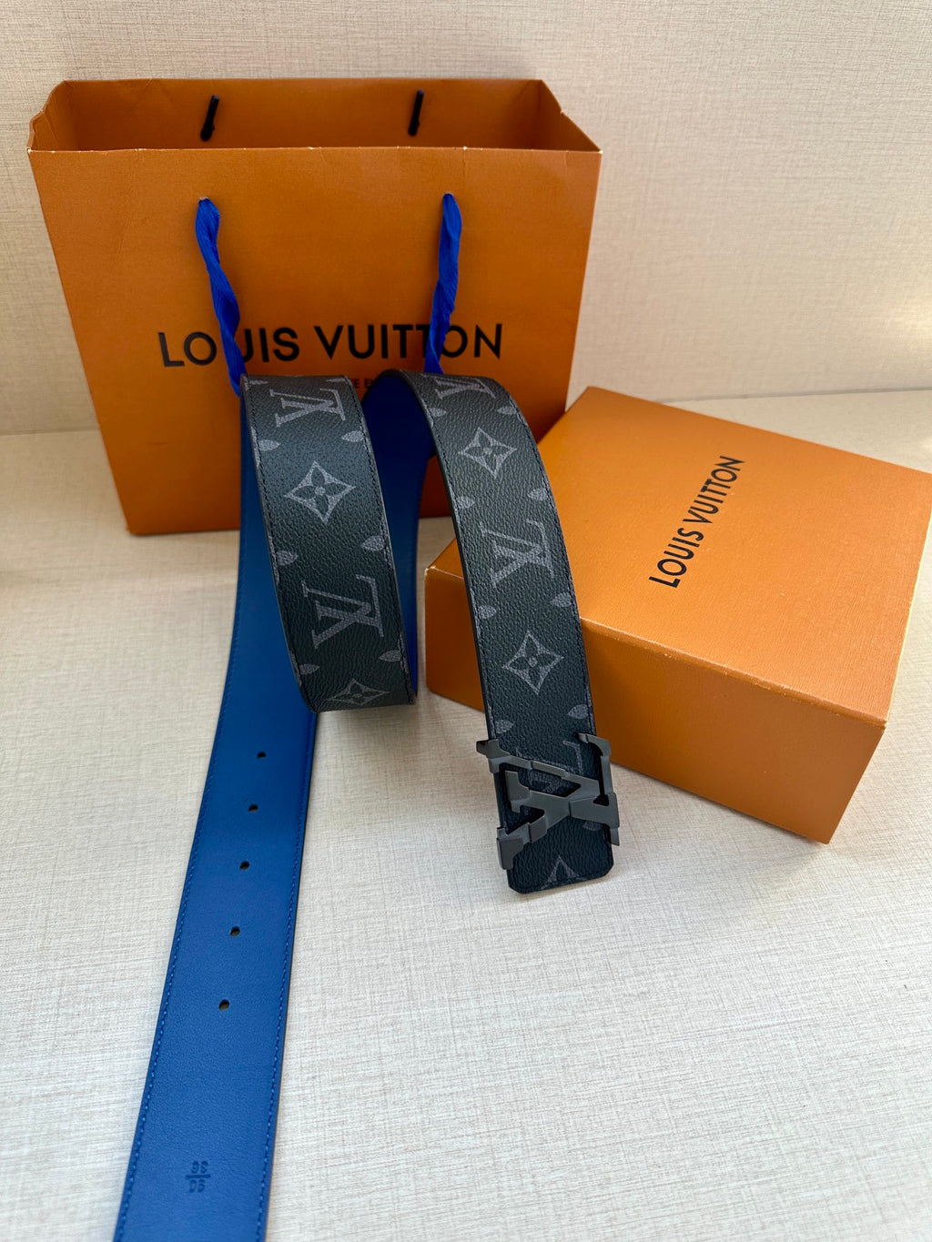 Louis Vuitton monogram belt with blue strap, metal buckle, and end holes visible