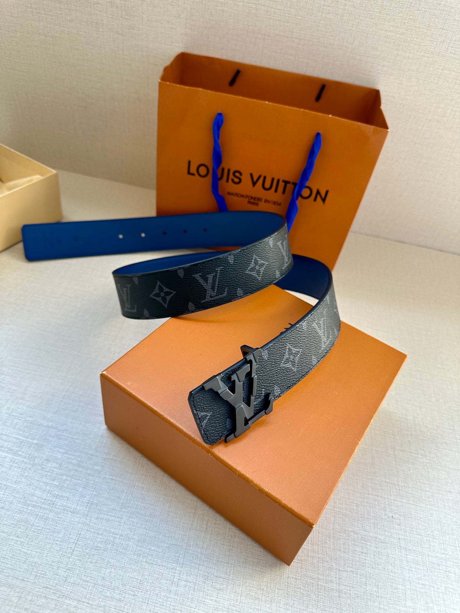 Louis Vuitton monogram belt laid flat with blue strap and metal buckle detail